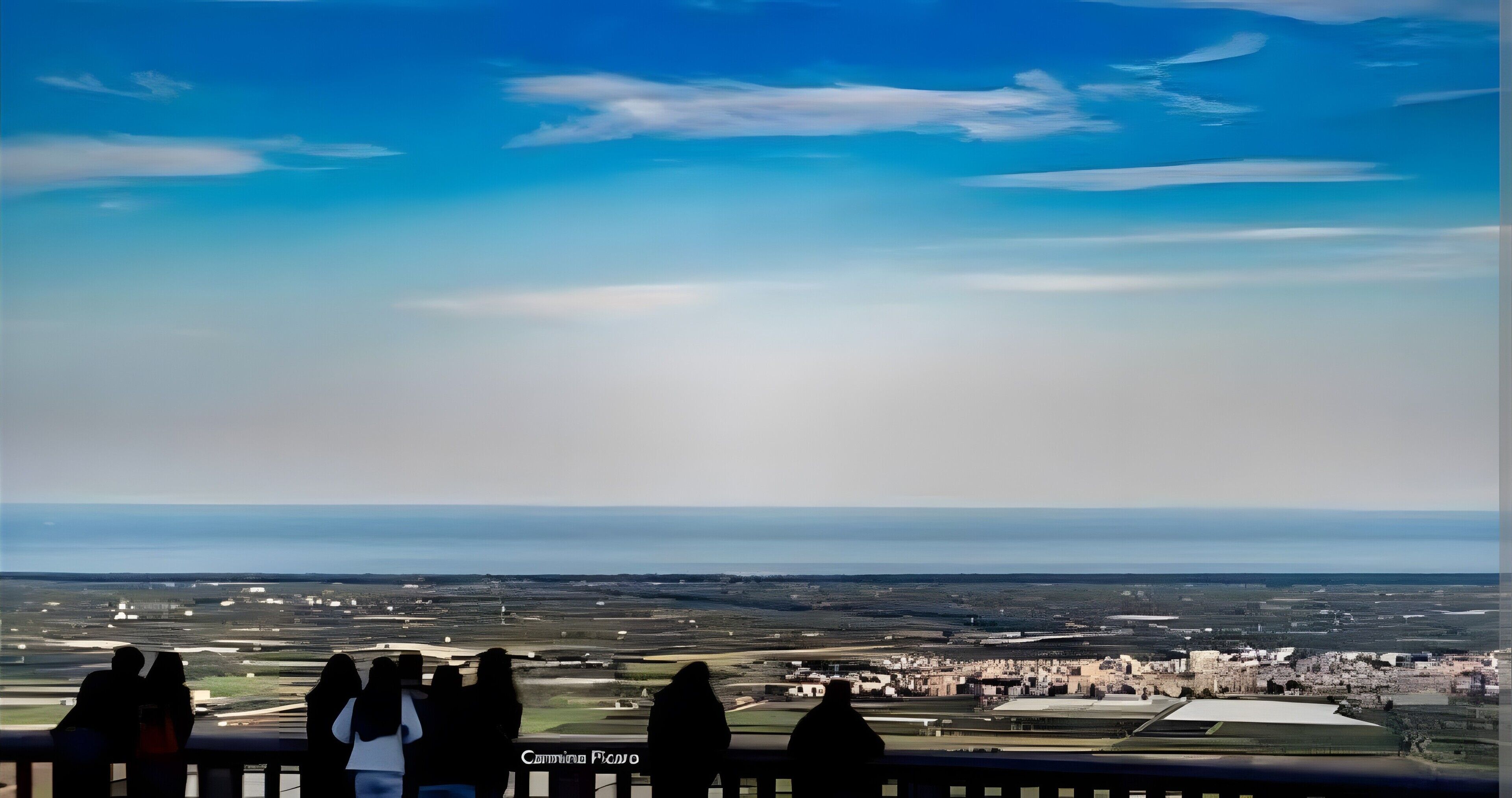Une vue depuis un balcon donnant sur un paysage côtier, avec une ville et un aéroport visibles au loin.