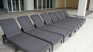 A row of six grey lounge chairs aligned outdoors with a tiled floor, near a building entrance with glass doors. - Riverine Diamond Rda12 Studio CK - Free 1 Parking, Netflix & Cozy Retreat Couples, Families (Kuching)