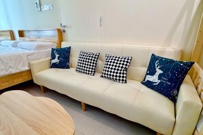 Une pièce comprenant un lit, un canapé agrémenté de coussins à motifs et une table ronde en bois.