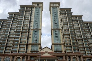 Ein Hochhaus mit mehreren Balkonen, einem zentralen Eingang und einer symmetrischen Fassade.