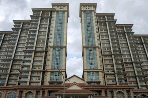 Un immeuble résidentiel de grande hauteur, doté de nombreux balcons, d’une entrée centrale et d’une façade symétrique.