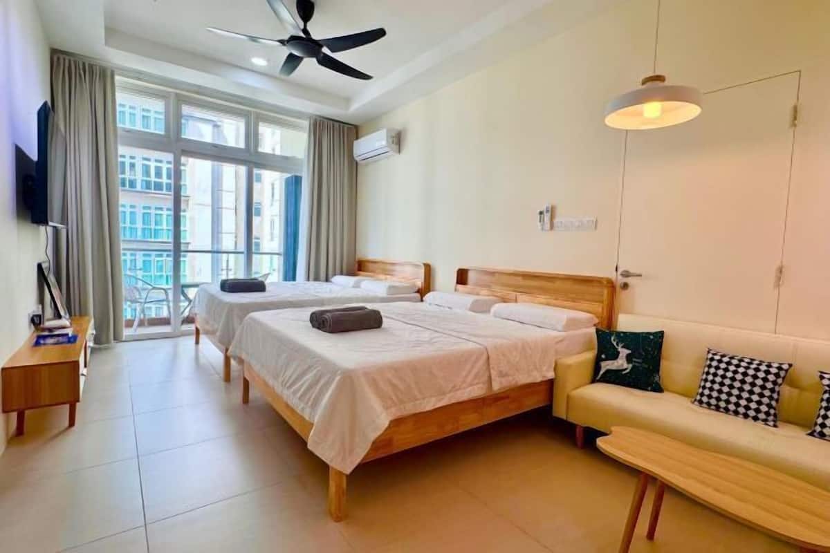 A hotel room with two beds, a sofa, a TV, and a balcony with curtains.