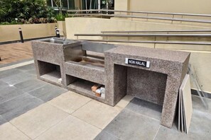 Un stand de restauration proposant des plats non halal, avec une enseigne, situé à l’extérieur sur un sol carrelé.