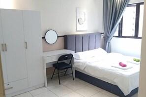 Een slaapkamer met een bed, een bureau, een stoel, een kledingkast en een raam met gordijnen.