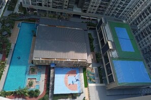 A multi-story building with a rooftop pool, a basketball court, and a tennis court.
