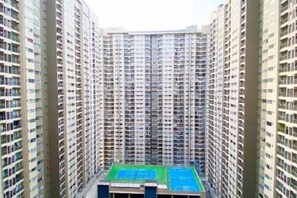 A high-rise building with multiple floors, a central courtyard with a green space, and a dense urban environment. - Nilai Youth City Residence C-25-15 (Nilai)