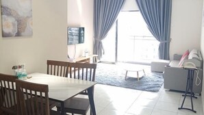 A living room with a dining table, chairs, a sofa, and a TV.