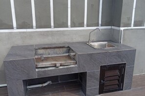An outdoor kitchen with a built-in sink and a grill area. - Nilai Youth City Residence C-25-15 (Nilai)