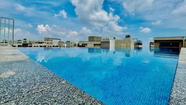 A swimming pool with clear blue water, surrounded by buildings and a clear sky.