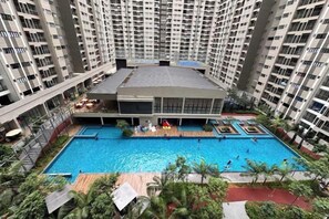 A multi-story residential building with a central swimming pool surrounded by greenery and a covered patio area. - Nilai Youth City Residence C-25-15 (Nilai)