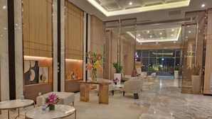 A hotel lobby with marble flooring, round tables, sofas, and artwork on the walls. - LISA HOUSE - MASTERI WEST HEIGHTS - VINHOMES SMART CITY (Hanoi)