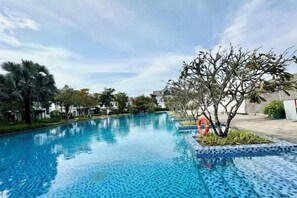 Une piscine à l’eau d’un bleu limpide, entourée de verdure et sous un ciel dégagé.