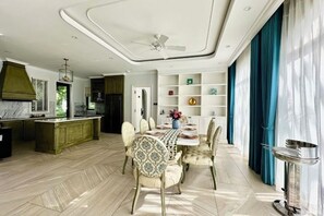Un vaste espace dédié à la salle à manger, doté d’un sol en marbre, d’un îlot central et d’un design de plafond moderne.