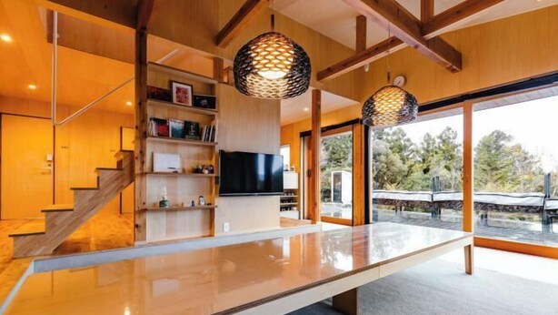 A modern interior with a large glass table, wooden beams, and a TV on a shelf. - SEN.RETREAT TAKAHARA (Tanabe)