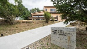 A stone sign with "ZEPHYR RETREAT" written on it, a concrete pathway, and a building in the background. - SEN.RETREAT TAKAHARA (Tanabe)