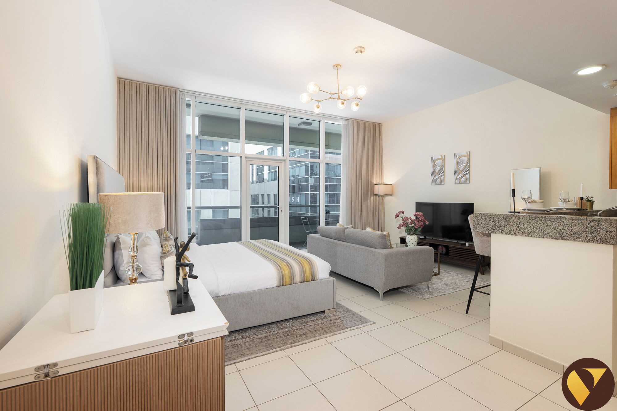A modern hotel room with a bed, a sofa, a TV, and a desk.