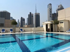 A rooftop pool with lounge chairs, a small table, and a potted plant. - Vogue | Bay Square Business Bay close to Dubai Mall | Burj Khalifa (Dubai)