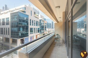 A balcony with a view of modern buildings, a railing, and a small table with chairs. - Vogue | Bay Square Business Bay close to Dubai Mall | Burj Khalifa (Dubai)