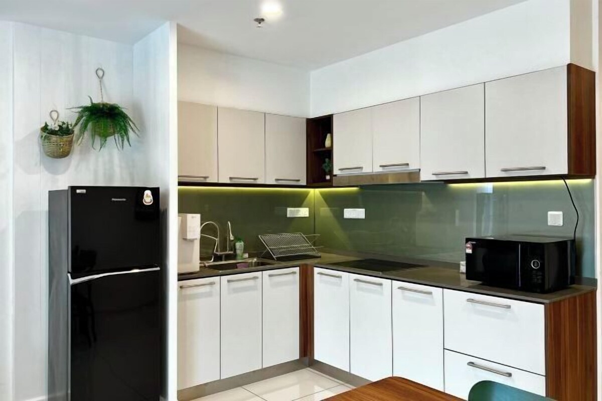 Cozinha moderna com armários brancos, geladeira preta, micro-ondas e backsplash verde.