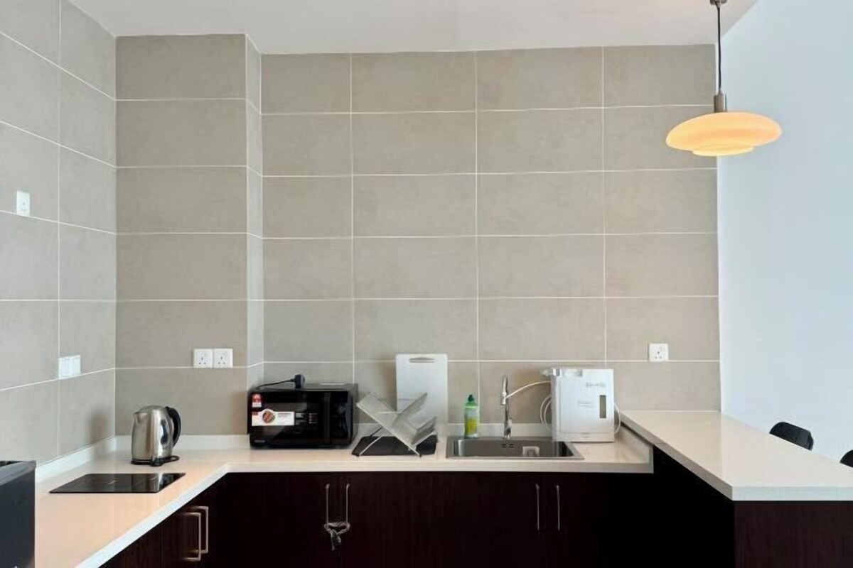 Uma cozinha moderna com forno embutido, máquina de café e chaleira.
