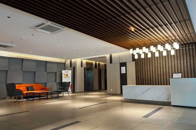 A modern reception area with a reception desk, a seating area with a sofa, and a patterned wall.