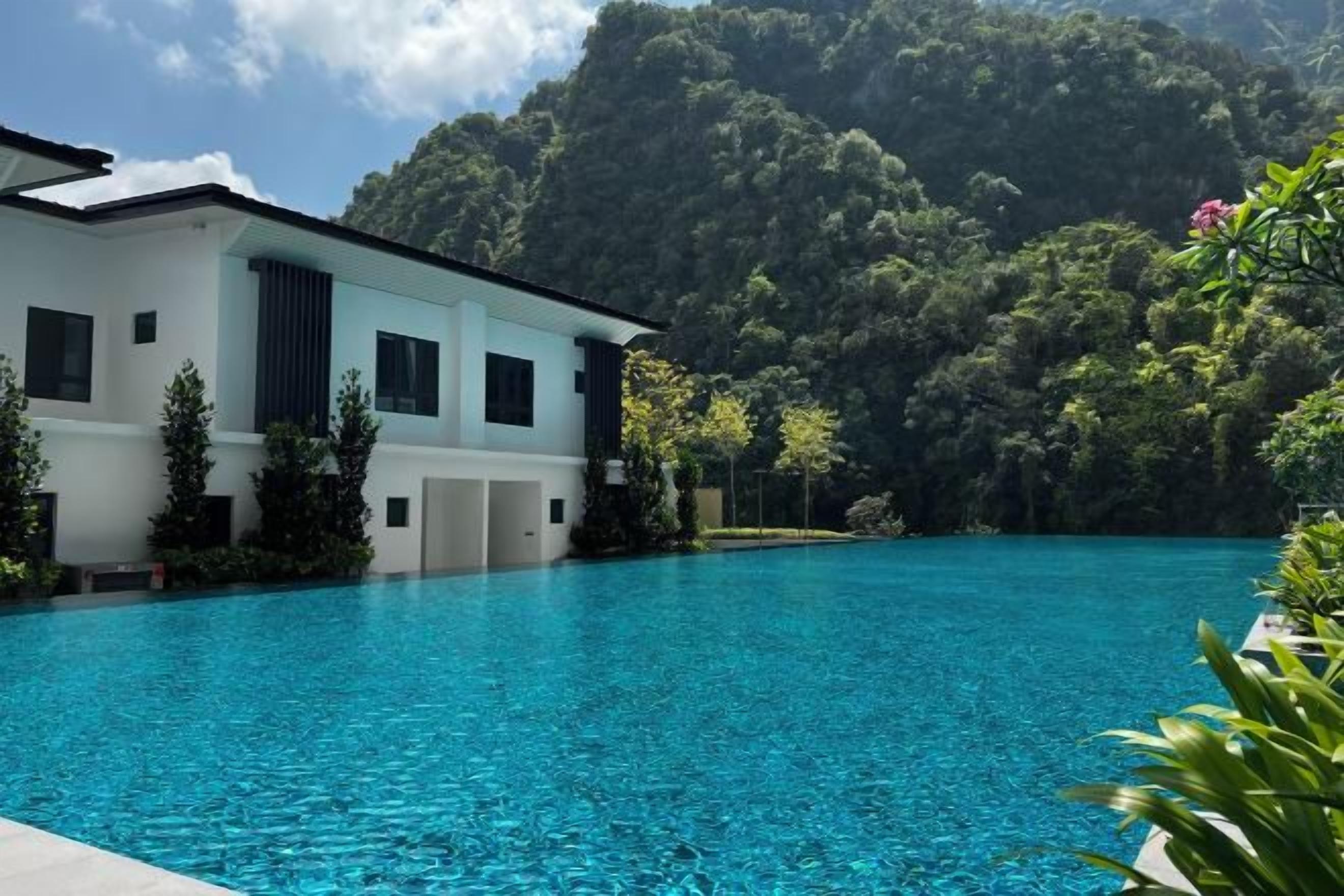 A modern building with a swimming pool in front, surrounded by lush greenery.