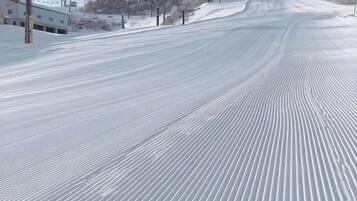 A snow-covered ski slope with ski lifts and buildings in the background.