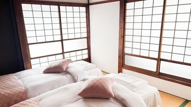 Ein traditioneller japanischer Raum mit Tatami-Böden, Shoji-Schirmen und zwei Betten mit pinken Laken.