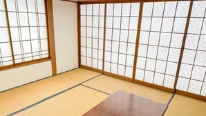Ein Raum mit Tatami-Matten, einem Holztisch und Shoji-Schirmen.