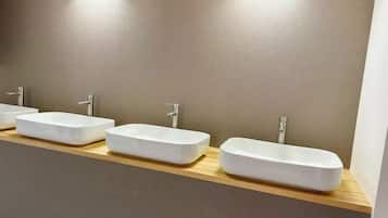 Tres lavamanos blancos y rectangulares sobre una encimera de madera en un baño.