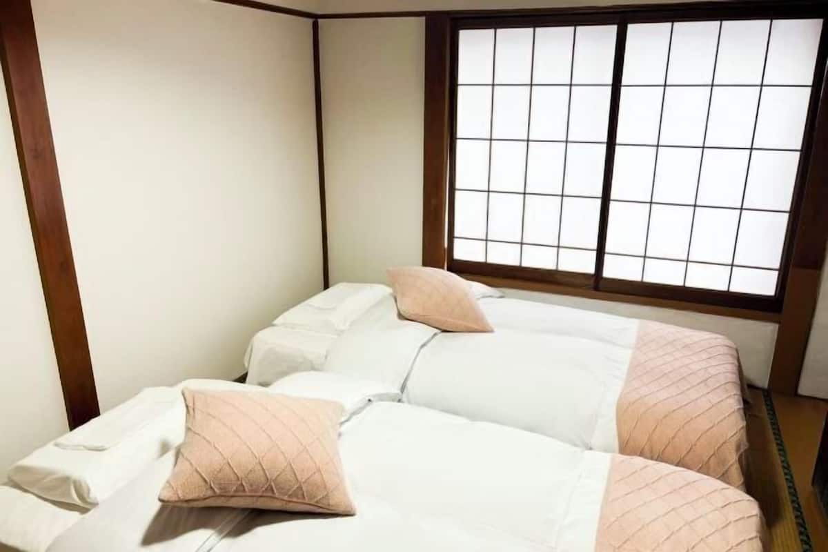 Quarto com cama, almofadas e janela com grade.