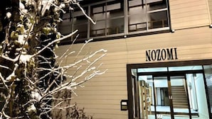Ein Gebäude mit der Aufschrift "NOZOMI" an der Fassade, mit modernem Design, großen Fenstern und einem gut sichtbaren Eingang.