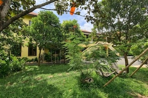 A courtyard with a tree, a small garden, and a building with a yellow facade.