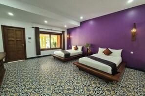 A hotel room with two beds, a large window with curtains, a patterned floor, and a purple accent wall. - Villa Romduol (Kampot)