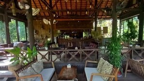 An outdoor seating area with wooden furniture and potted plants. - Villa Romduol (Kampot)