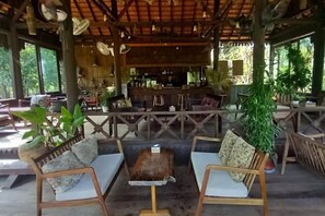 An outdoor seating area with wooden furniture and a bar in the background.