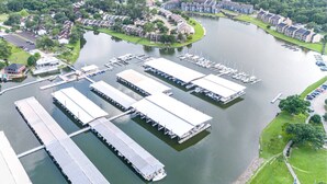 Un puerto deportivo con varios muelles y barcos, rodeado de edificios residenciales y vegetación.