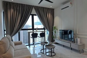 A modern living room with a sofa, two chairs, a TV, and a large window with curtains.