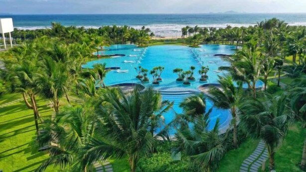 Ein Resort mit mehreren Pools, umgeben von Palmen und Blick auf den Ozean.