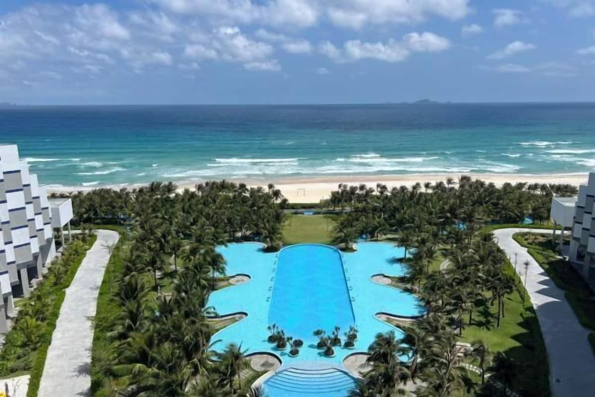 A resort with a central pool, beachfront, and modern architecture.