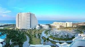 Ein modernes Hotel mit markant kurviger Architektur, einem zentralen Innenhof und Blick auf das Meer.