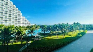 Ein Resort mit einem großen Gebäude, einem Swimmingpool, Palmen und einem Weg.