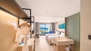 Ein modernes Hotelzimmer mit Bett, Schreibtisch, Schminktisch und Meerblick.