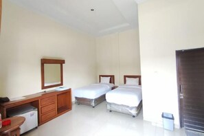Een hotelkamer met twee eenpersoonsbedden, een houten bureau met spiegel, een klein tafeltje en een prullenbak.