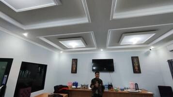 A conference room with a flat-screen TV, a wooden table, and a bar area.