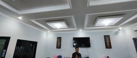 A conference room with a flat-screen TV, a wooden table, and a bar area.