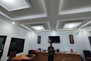 A conference room with a flat-screen TV, a wooden table, and a bar area. - HOTEL CIWANGI (Bungursari)