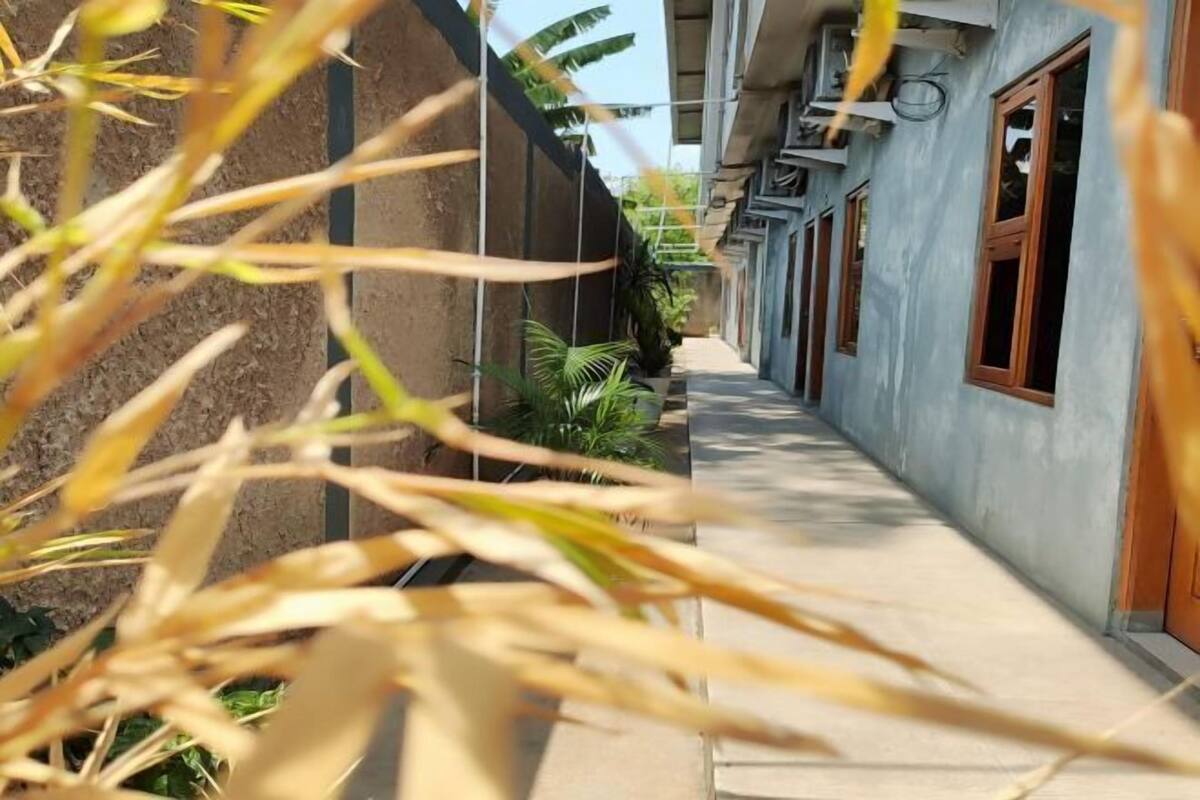 A narrow corridor with a concrete floor, flanked by buildings with wooden doors and windows.