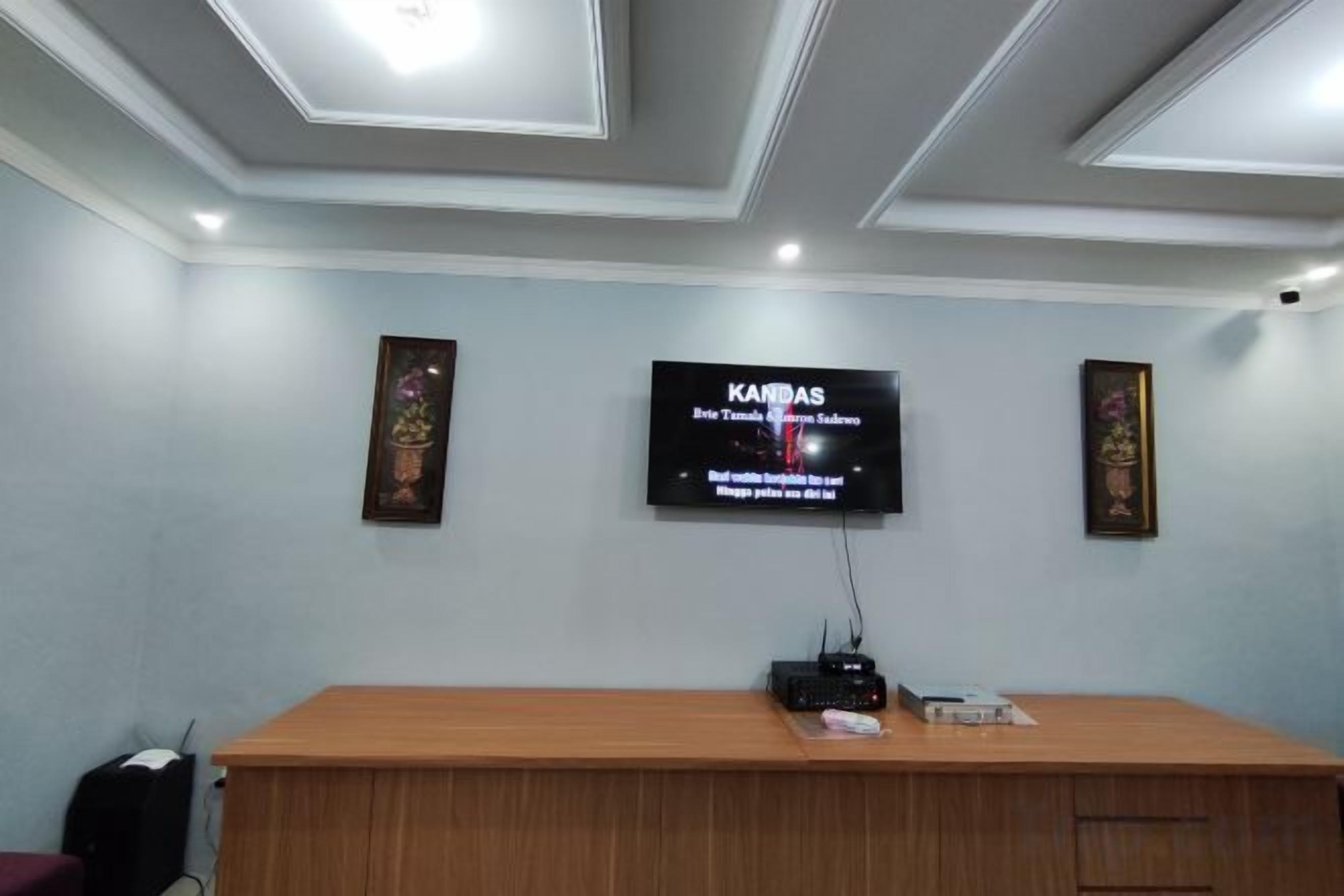 A reception area with a wooden desk, a flat-screen TV mounted on the wall, and framed artwork on either side.