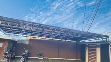 A covered outdoor area with a metal roof structure, a brown wall, and a motorcycle parked to the side.